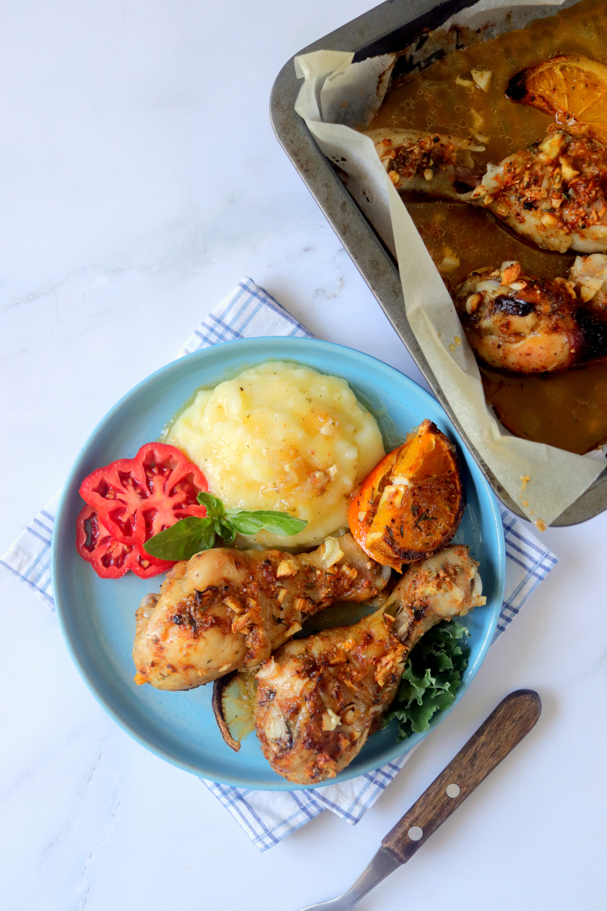 plate of chicken drumsticks next to baking pan.
