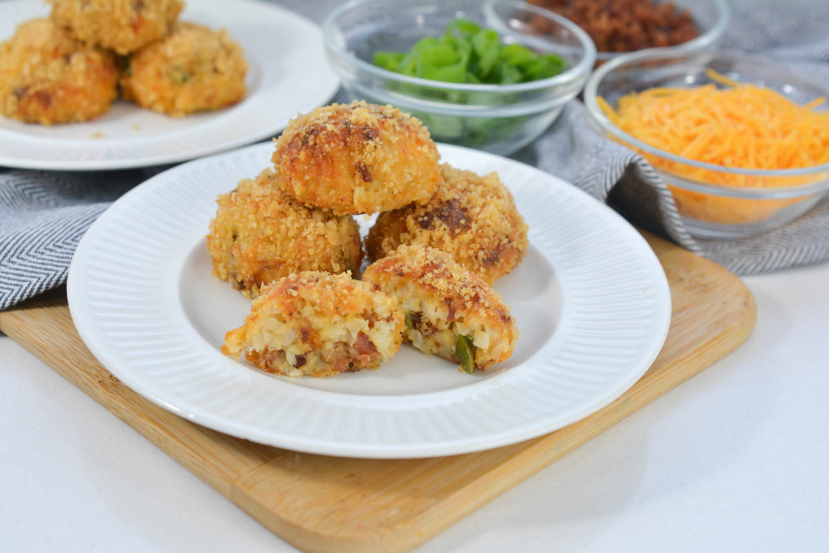 Rice balls on a plate in front of ingredients in individual bowls.