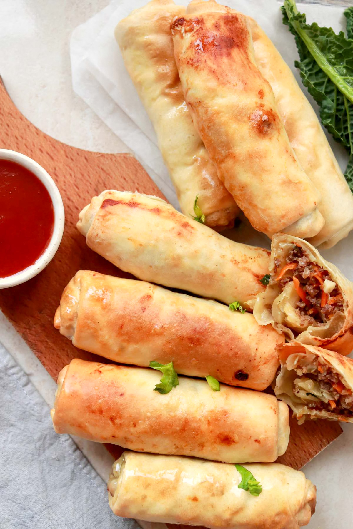 Egg rolls on a cutting board with dipping sauce.