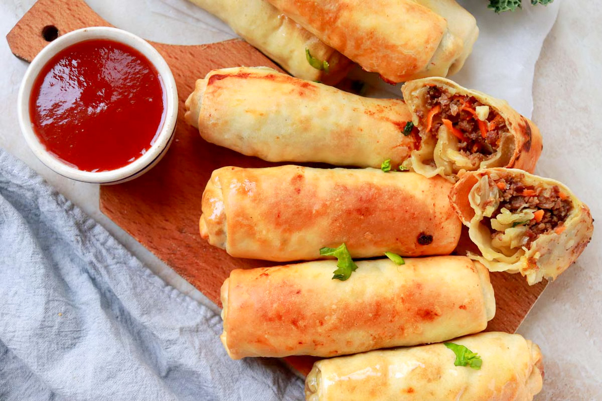 Egg rolls on a platter and one is cut in half.