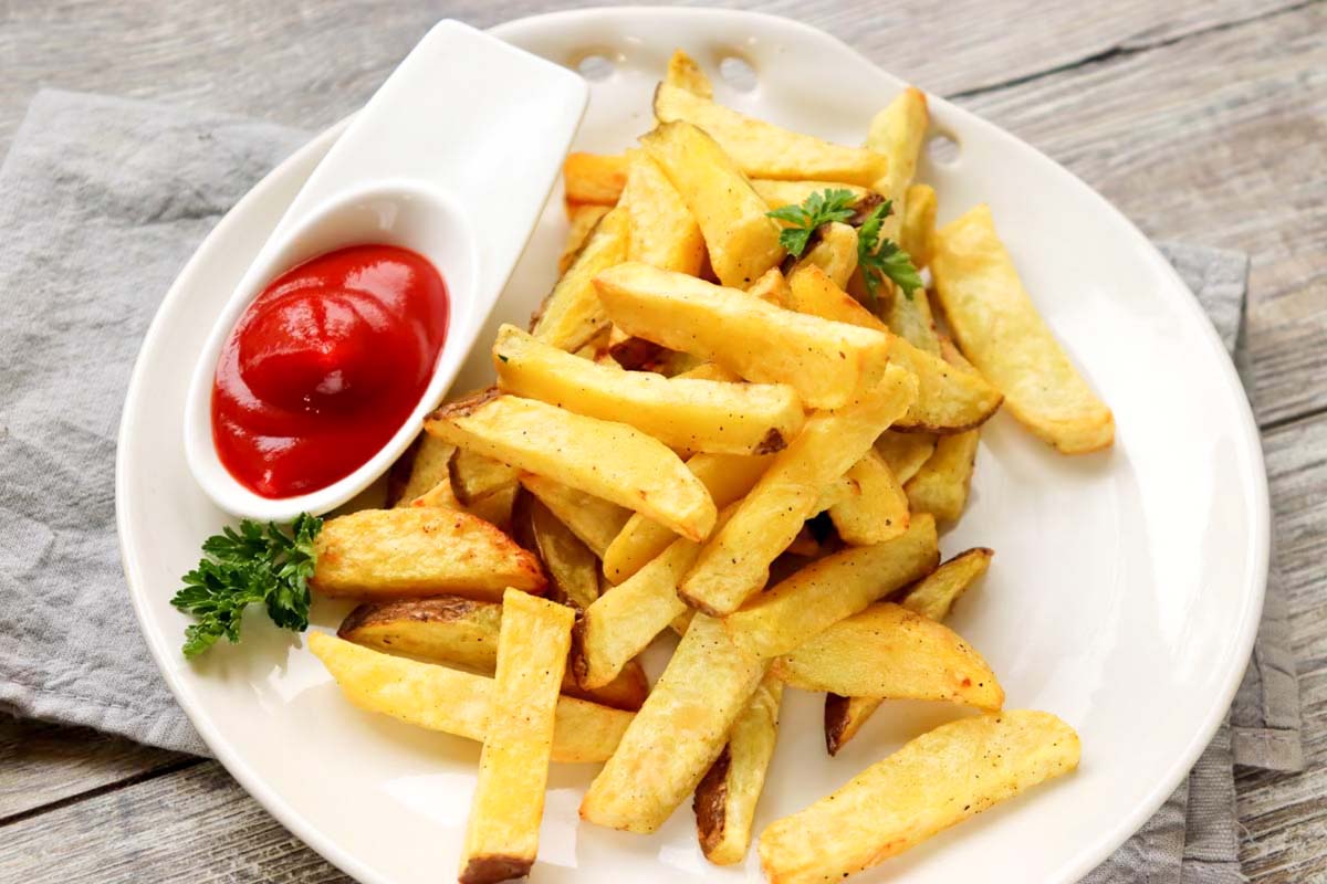 Fries on a plate with ketchup.