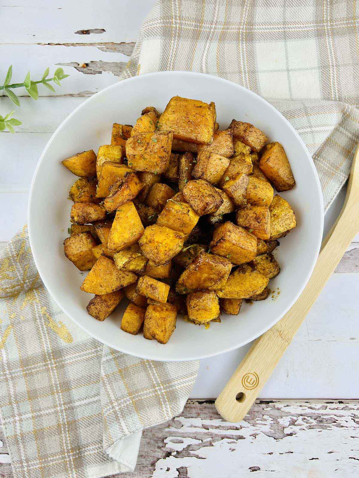 Cubed squash in a white bowl set on a beige kitchen towel.