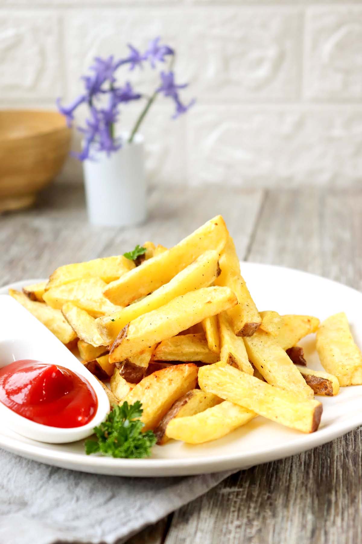 Fries on a plate set on a wood table.