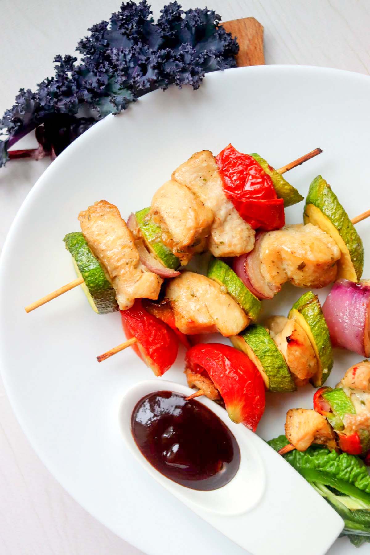 Kabobs on a white plate with dipping sauce.
