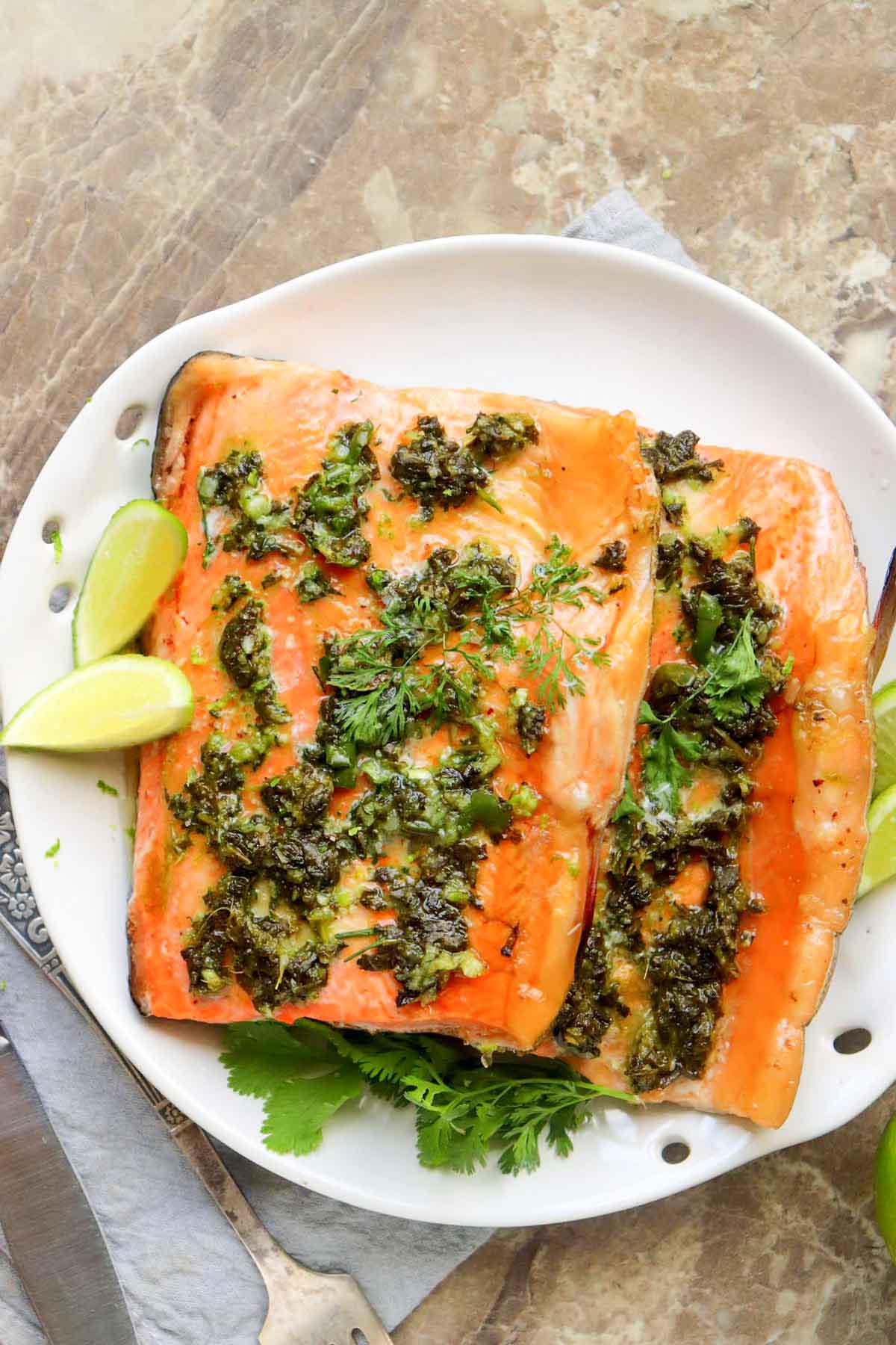 Salmon fillets on a plate with lime wedges.