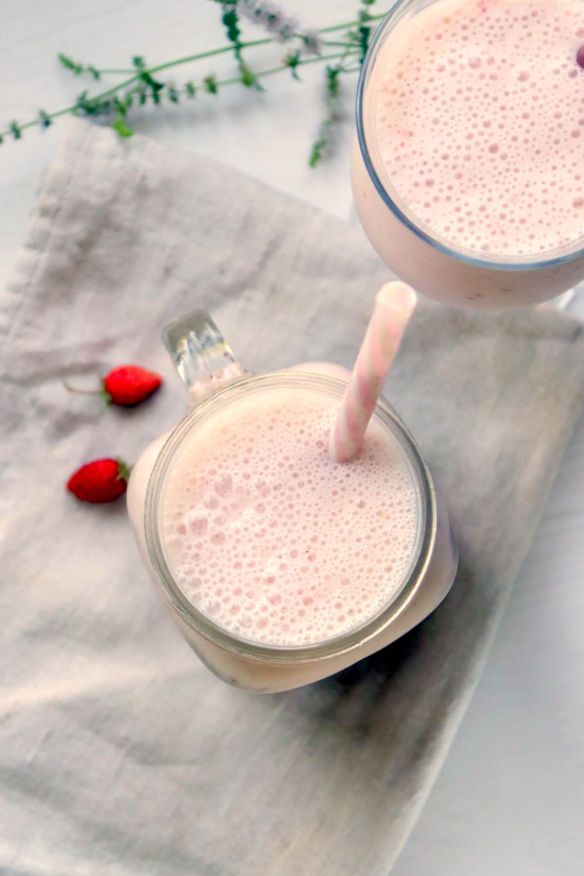 Two smoothies in glasses sitting on a kitchen towel.