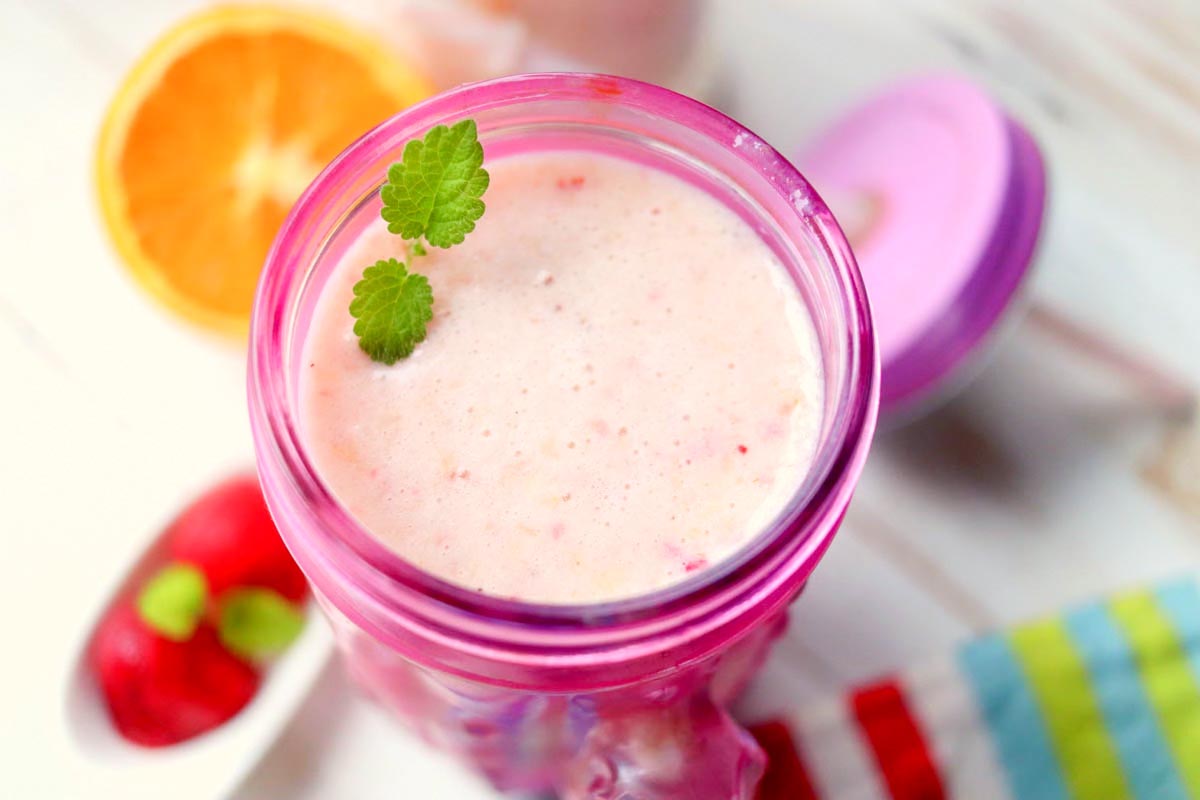 Fruit smoothie with a sprig of mint on top.