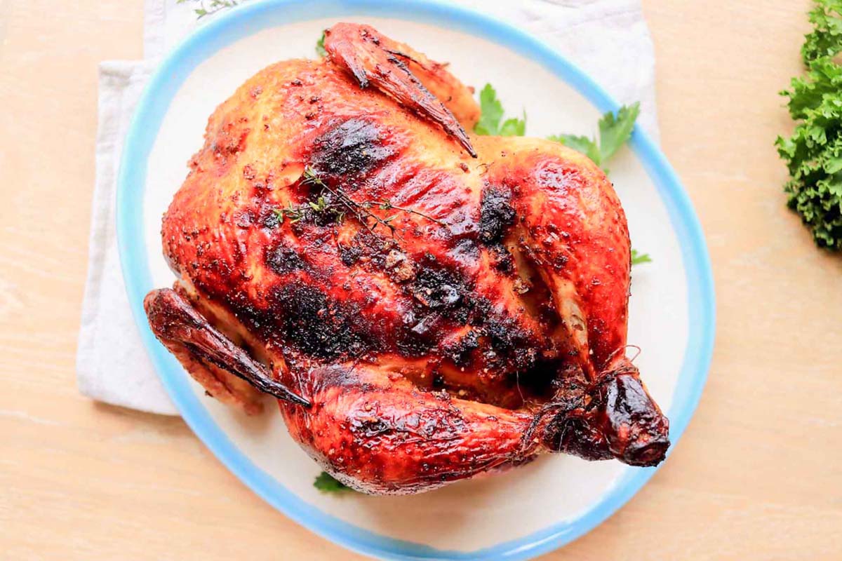 Whole cooked chicken on a white and blue plate.