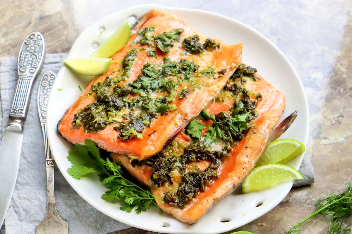 Two salmon fillets on a white plate.