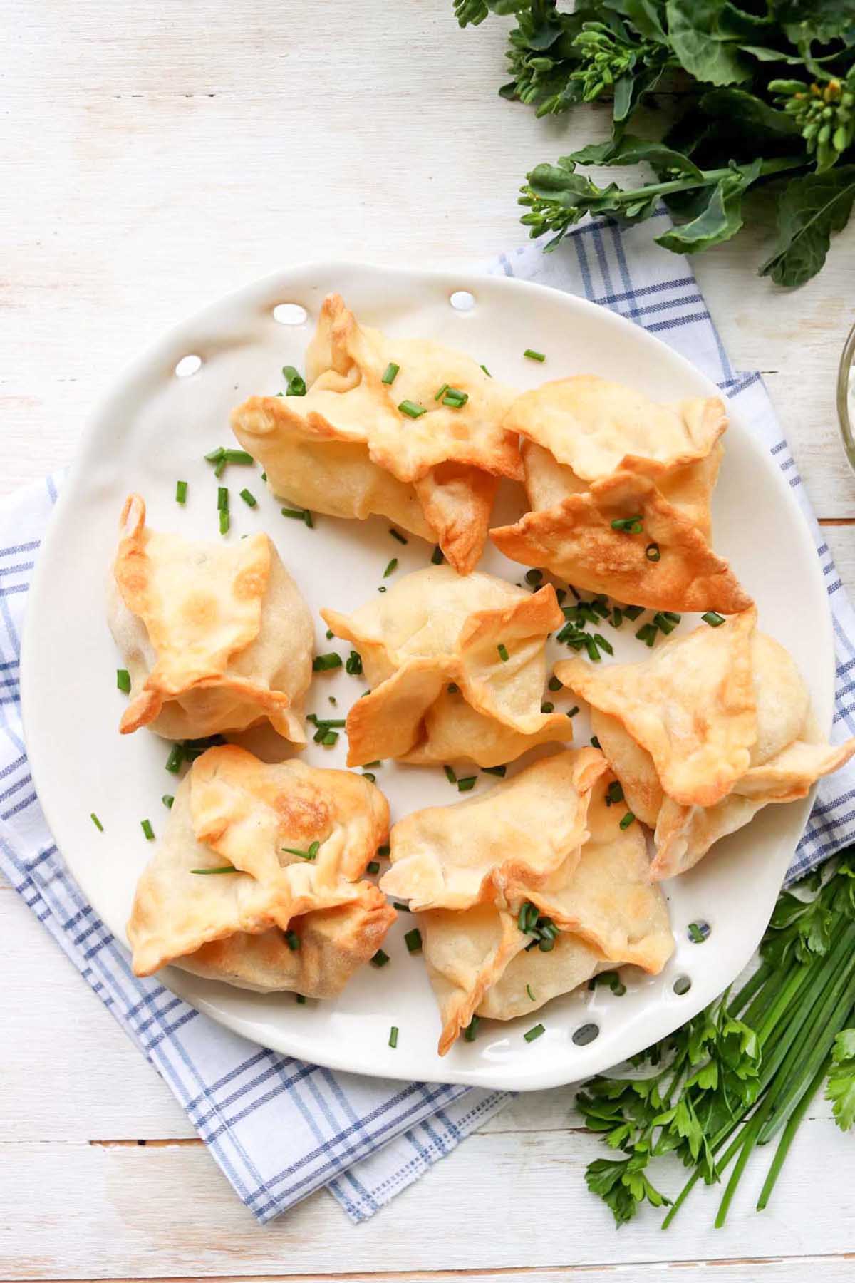 Wontons on a plate set on a kitchen towel.