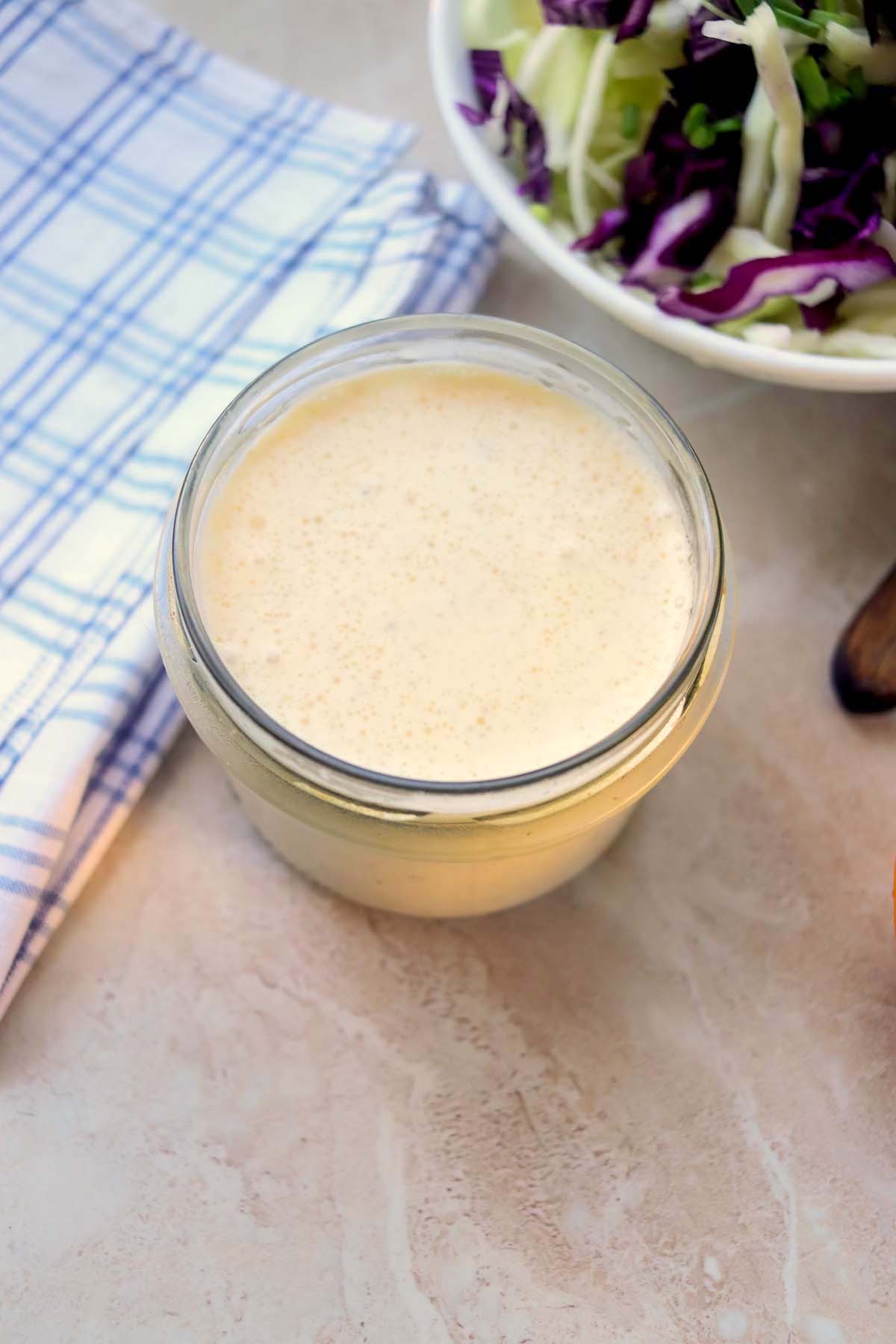 Dressing in a jar next to a kitchen towel.