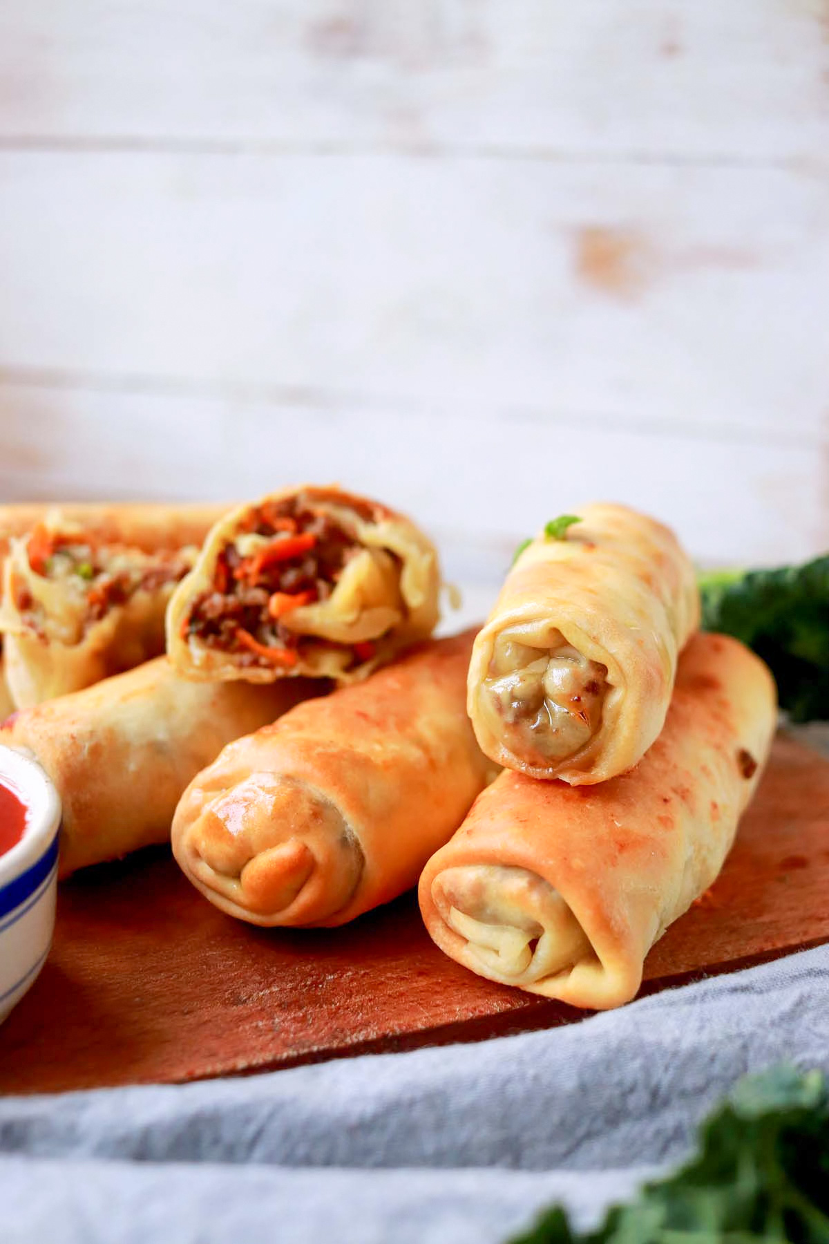 Egg rolls on a cutting board with a dipping sauce.