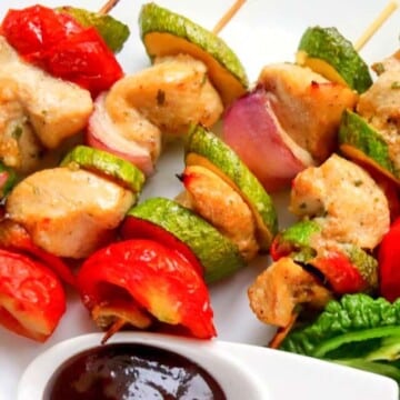 Chicken kabobs on a plate with dipping sauce.