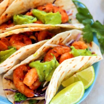 five shrimp tacos on a plate.