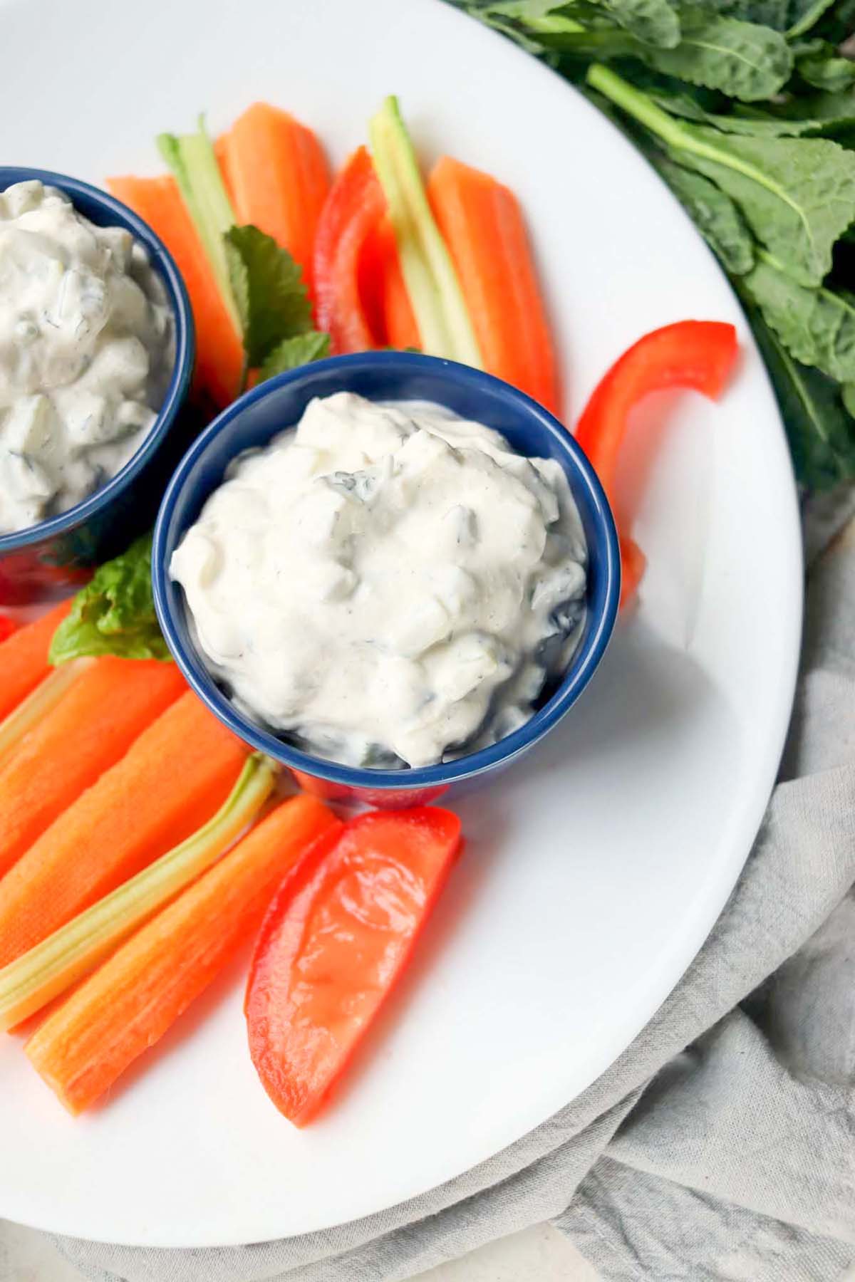 cucumber dill dip on a plate with carrots sticks.