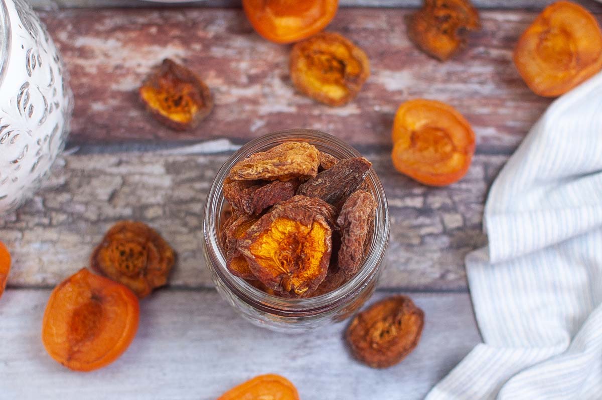 Dried apricots in a jar set on a wood table.