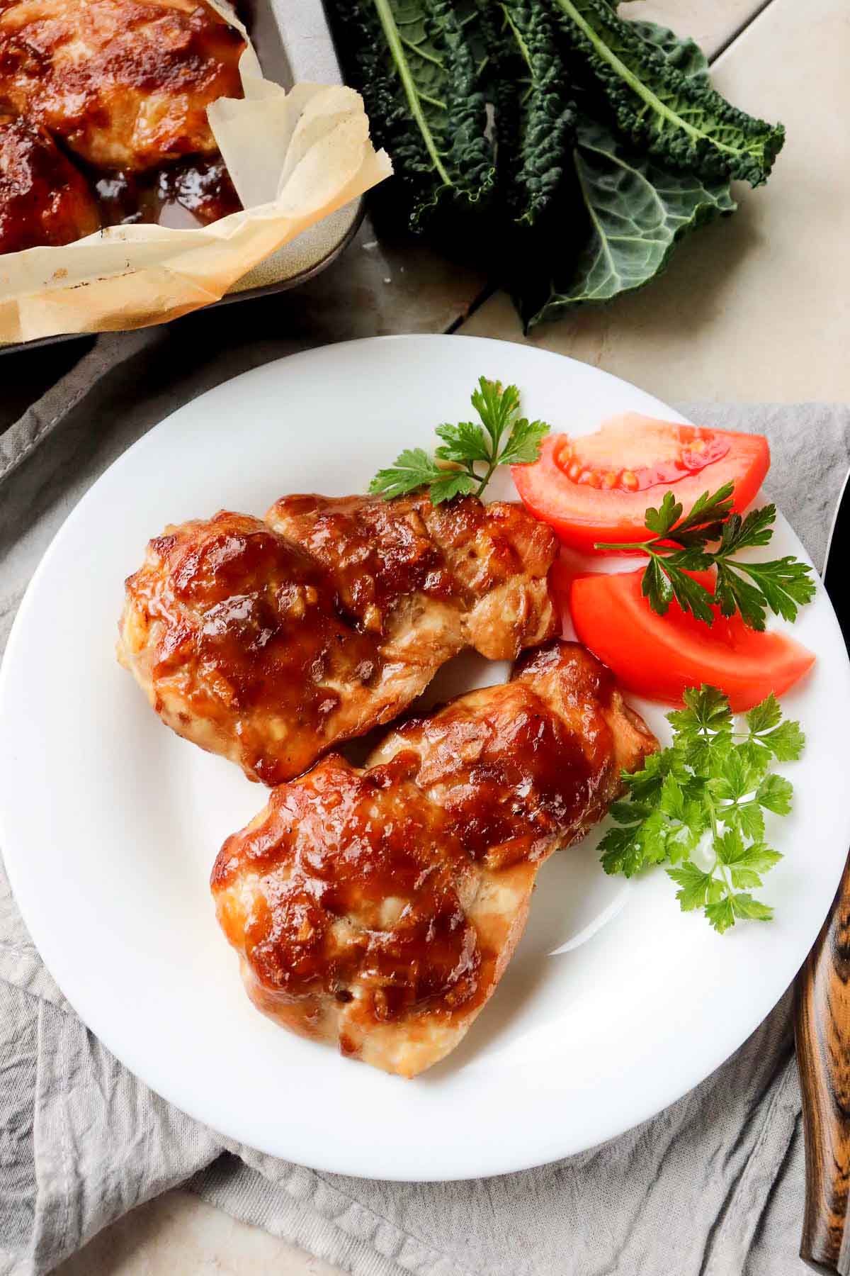 Two chicken thighs on a white plate.