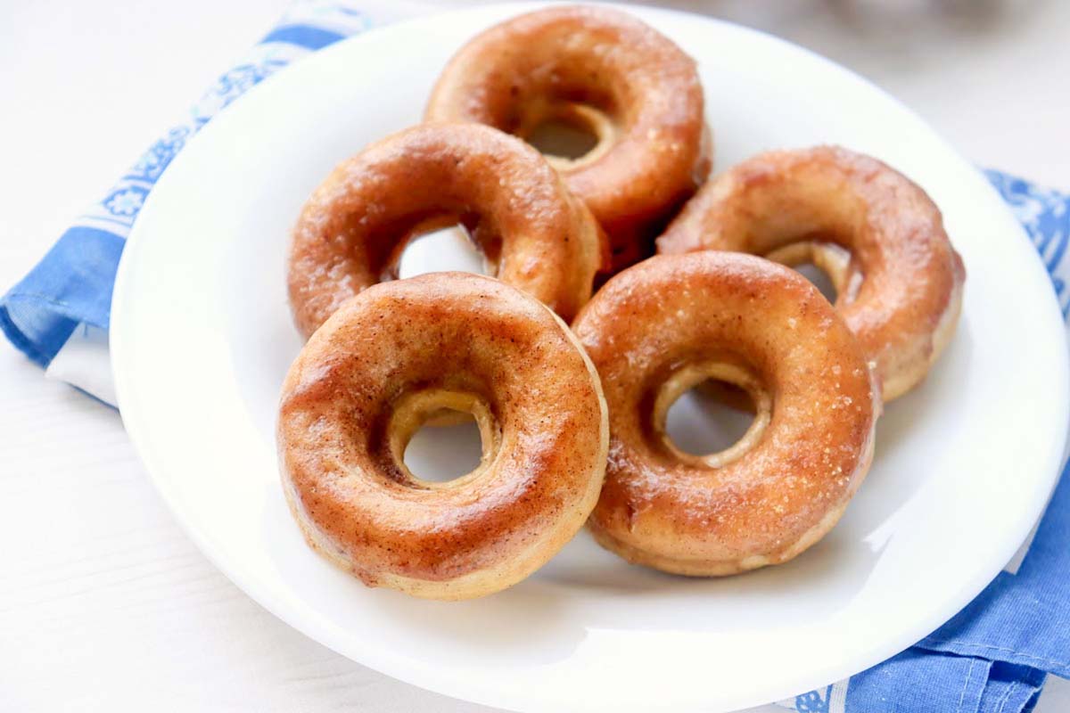 Five donuts stacked on a white plate.
