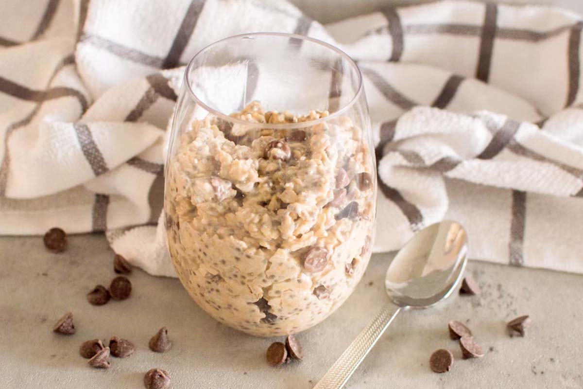 Oats in a glass with a spoon next to it.