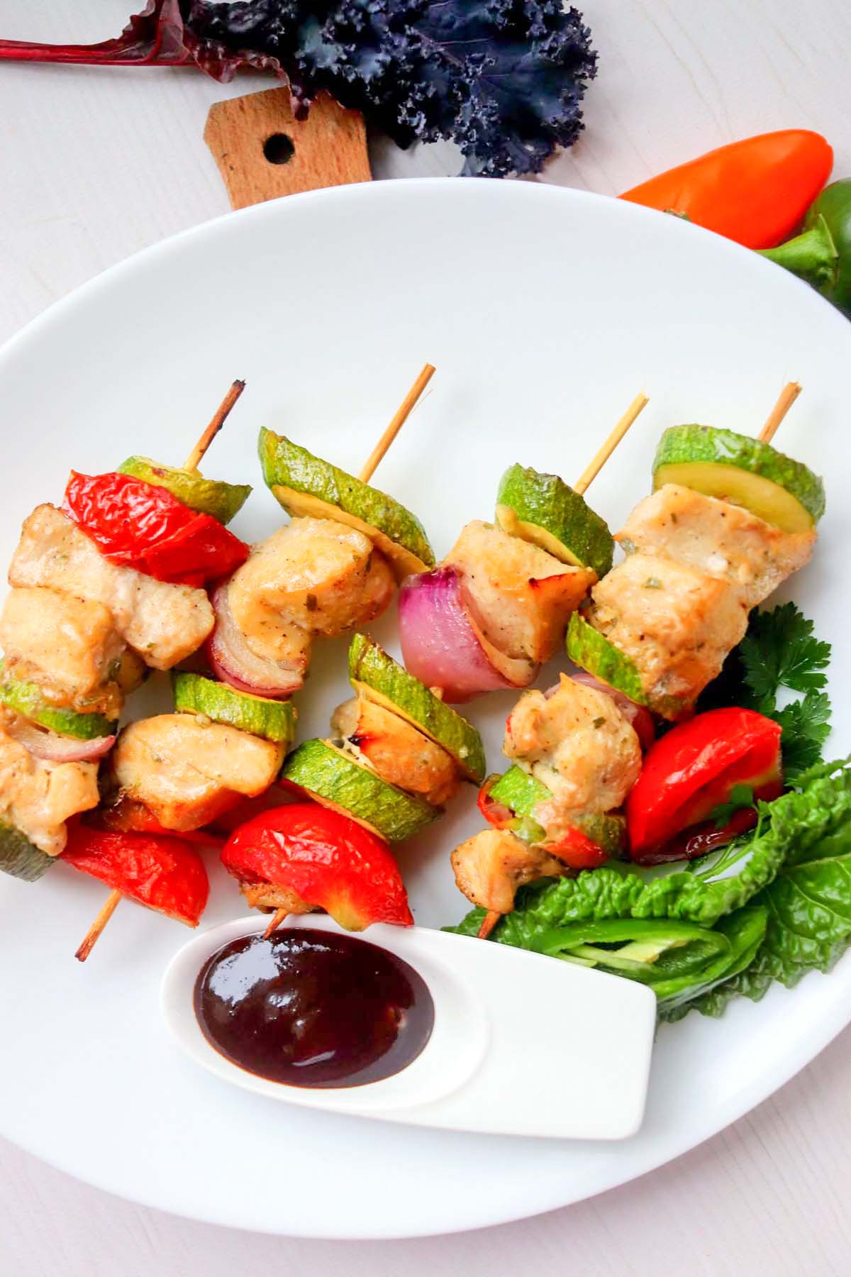 Four chicken kabobs on a plate.