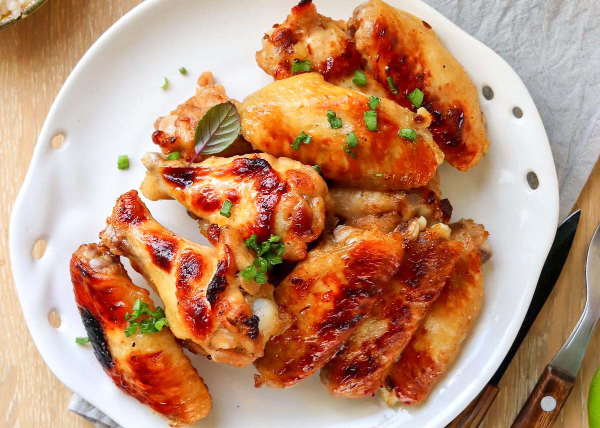 Chicken wings on a plate set on a kitchen towel.