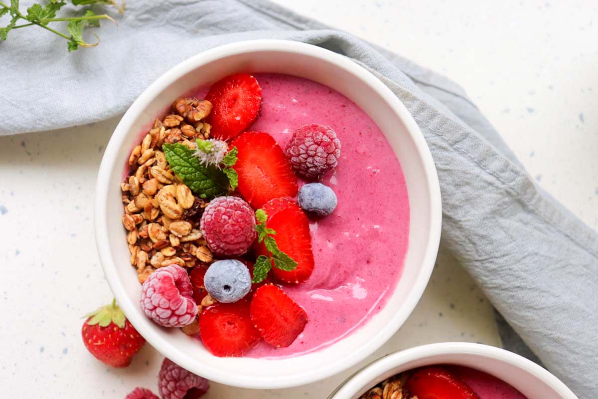 Pink smoothie bowl topped with fruit.
