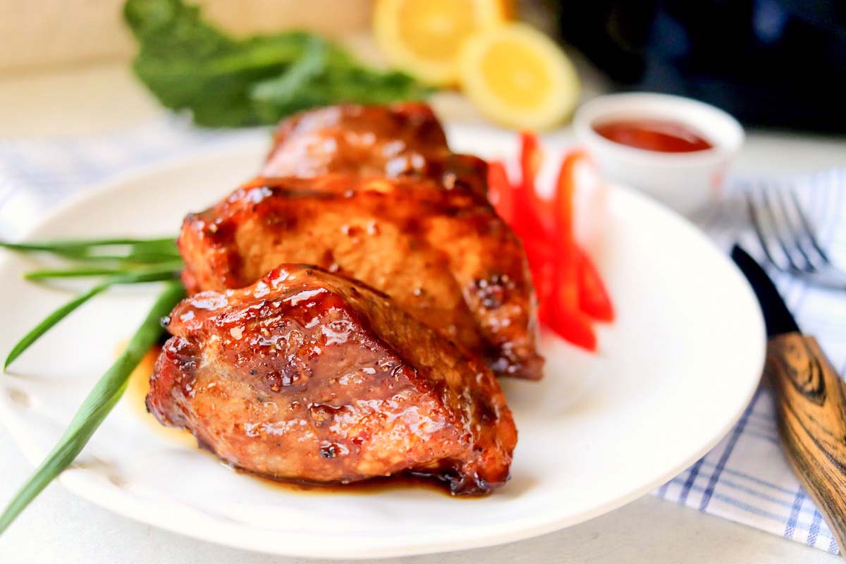 Pork chops on a plate with garnishes.