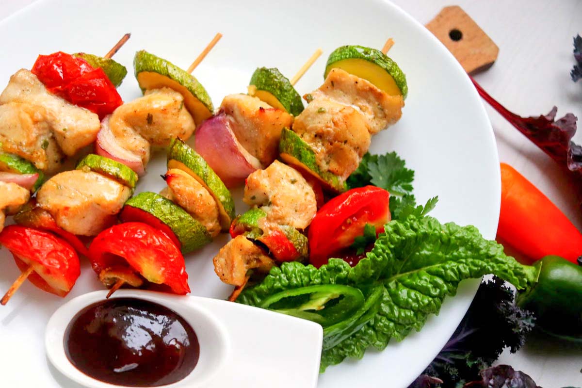 Chicken kabobs on a plate with dipping sauce.