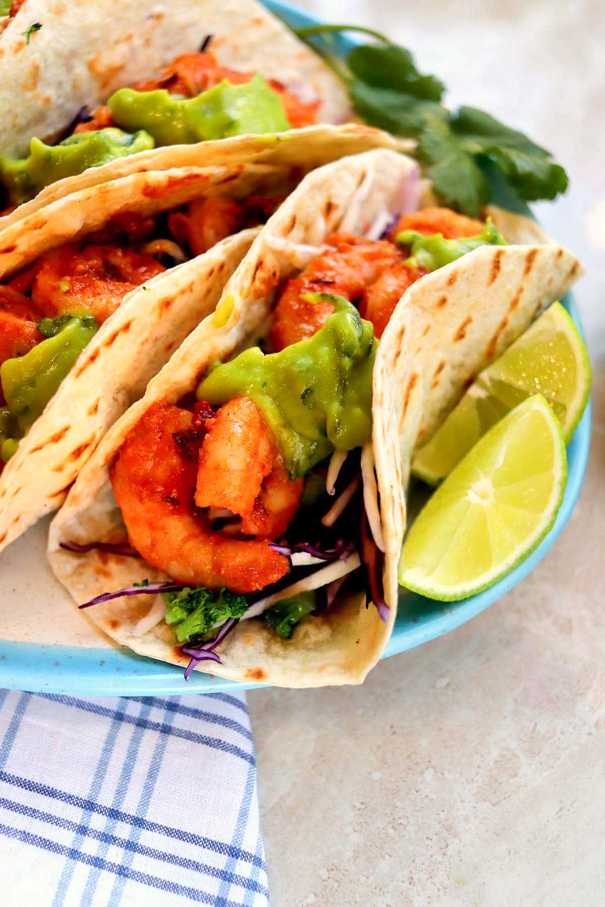 shrimp tacos on a plate with sliced limes.