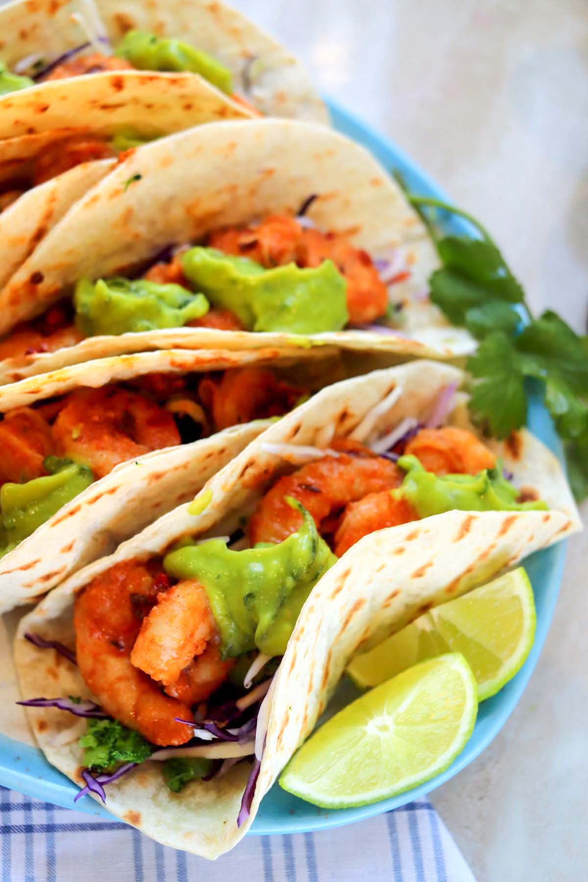 Five shrimp tacos on a plate.