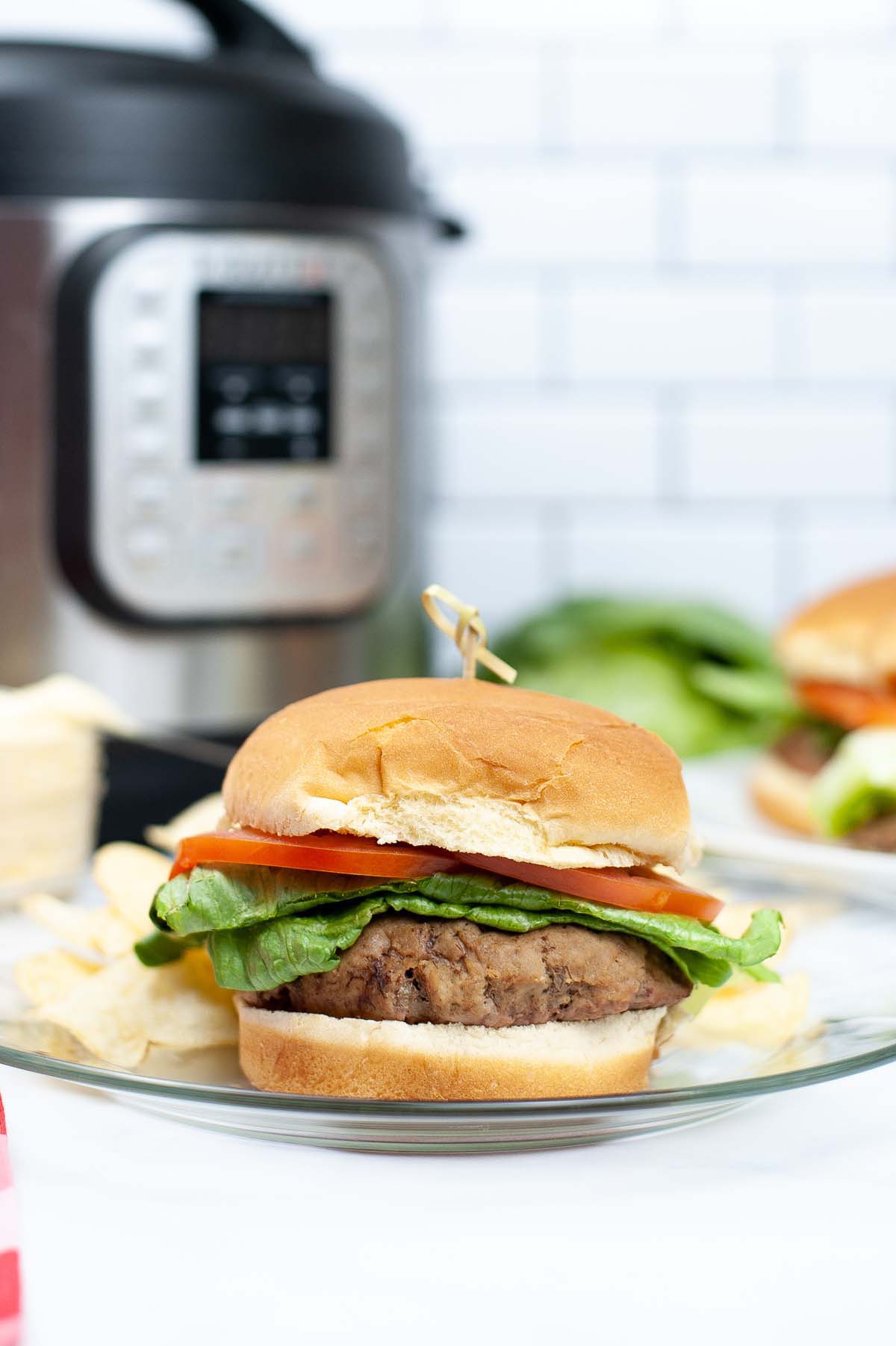 Burger on a plate in front of the Instant Pot.