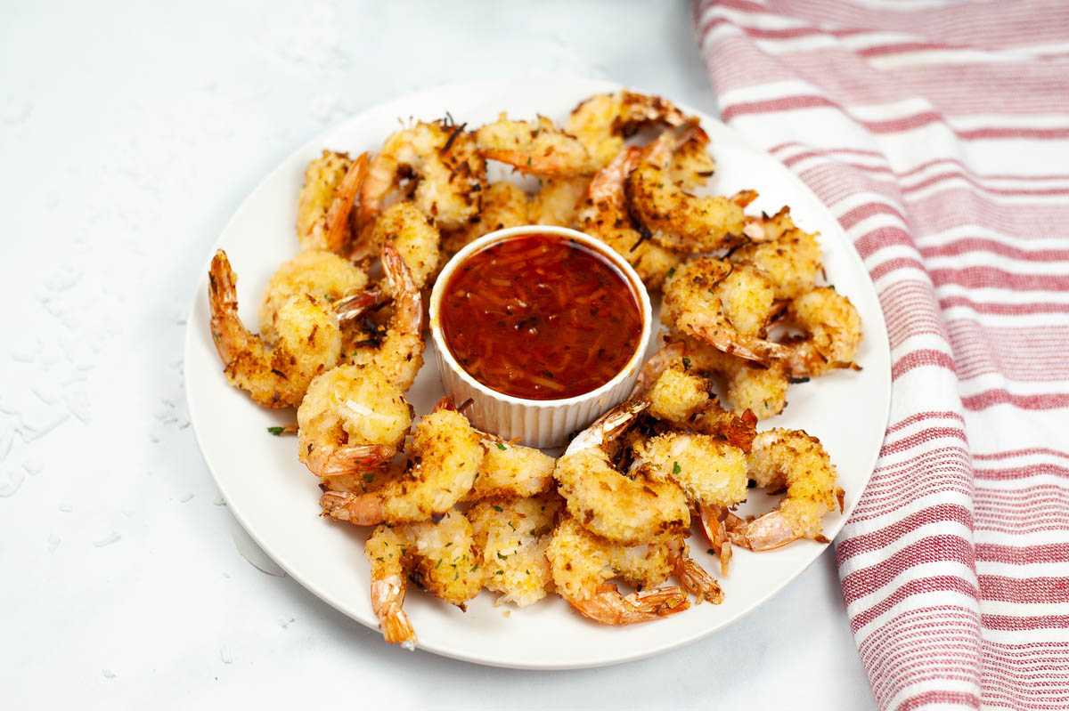 Coconut shrimp on a plate with dipping sauce.