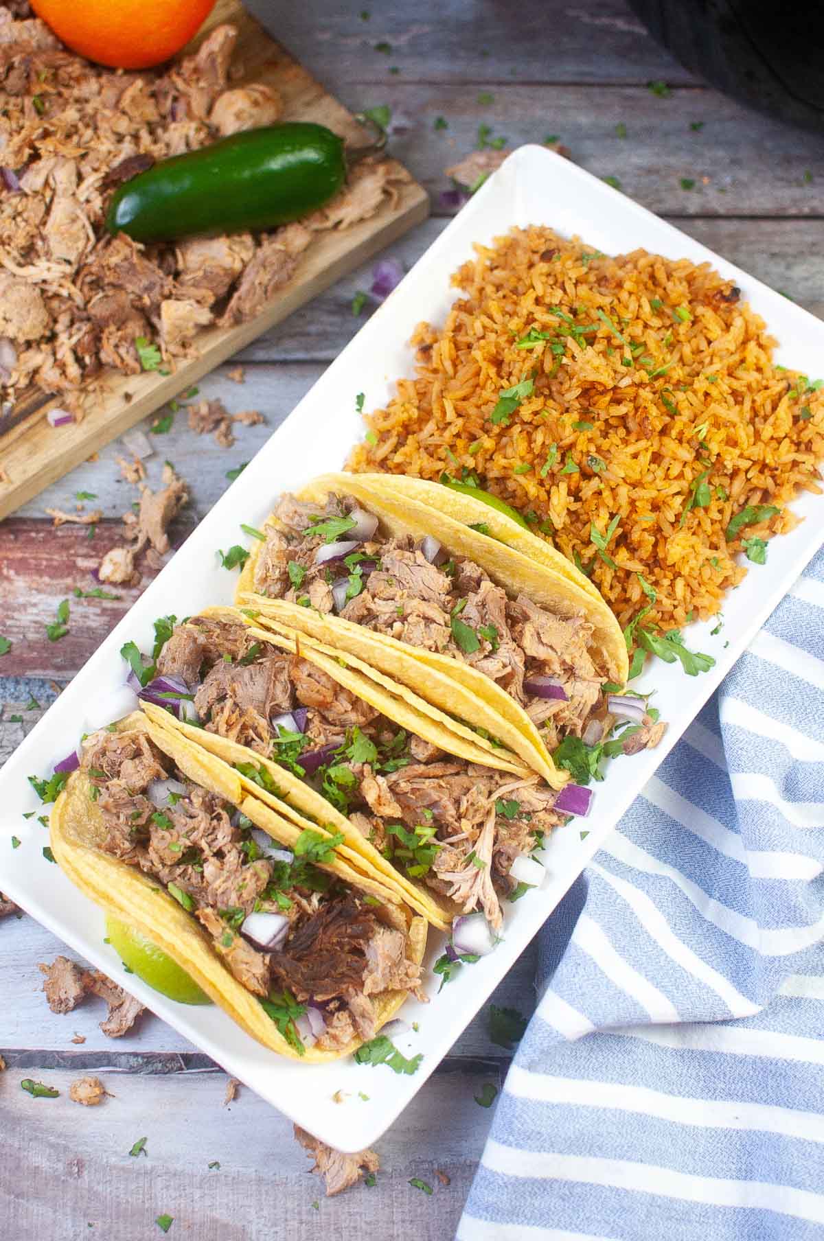 three tacos on a plate with rice.