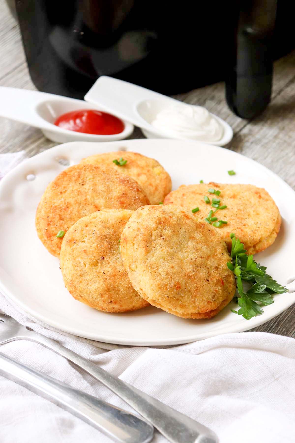 Potato patties on a plate with dipping sauce.