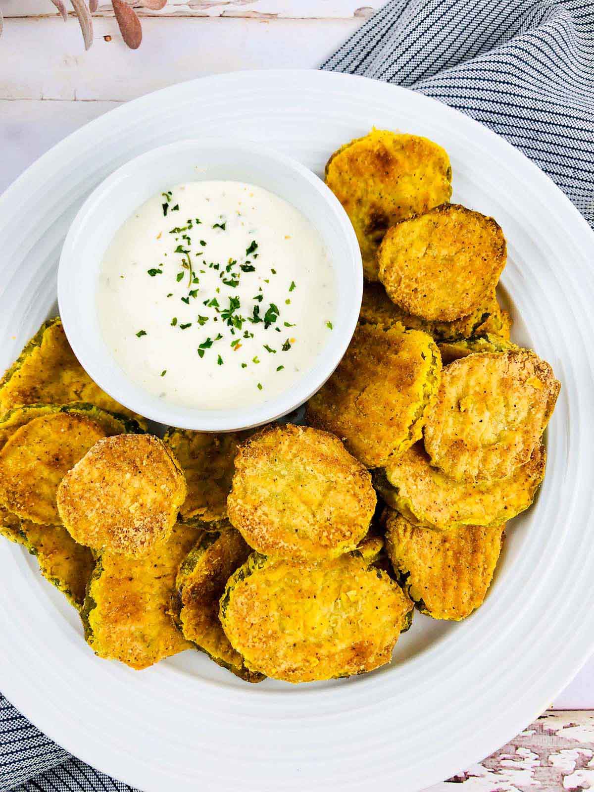 Pickles on a plate with a white dipping sauce.