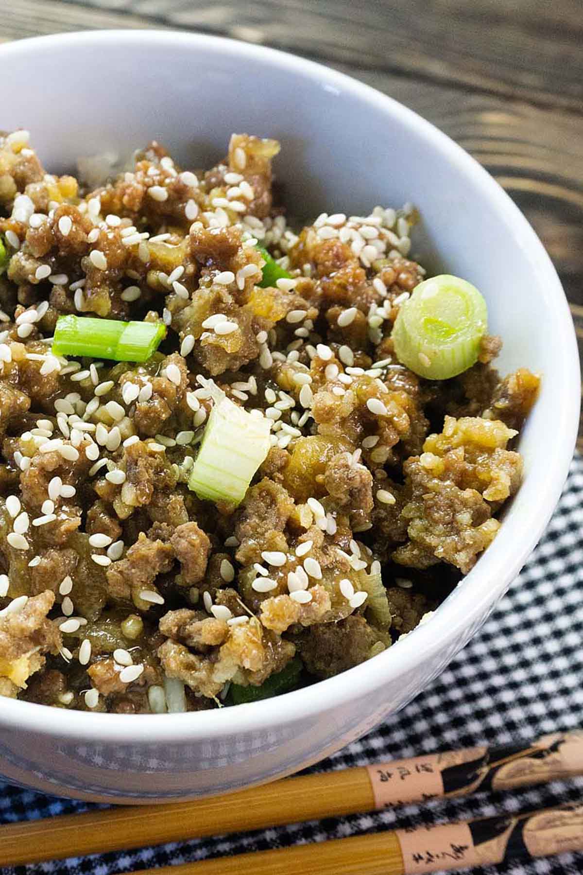 Beef in a bowl topped with chopped scallions.