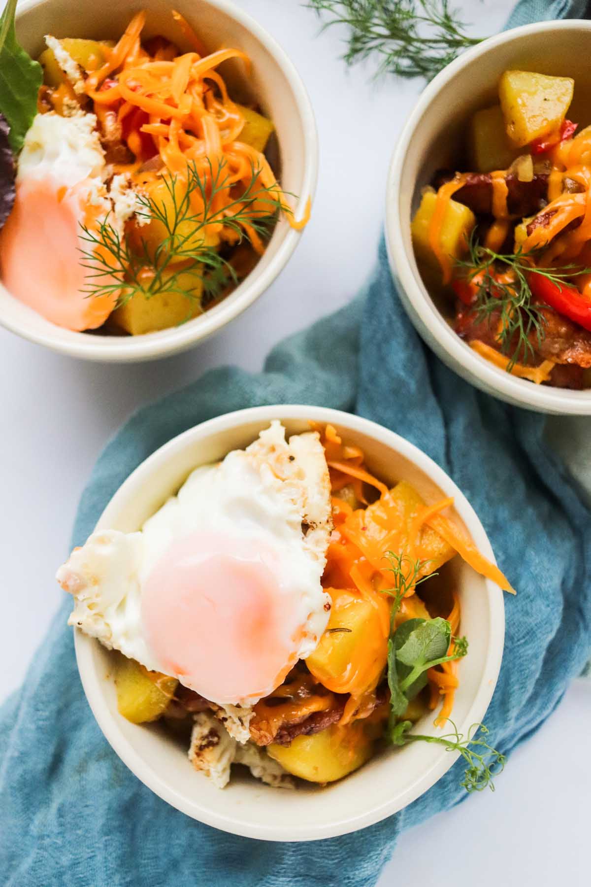 breakfast hash in bowls topped with a fried egg.