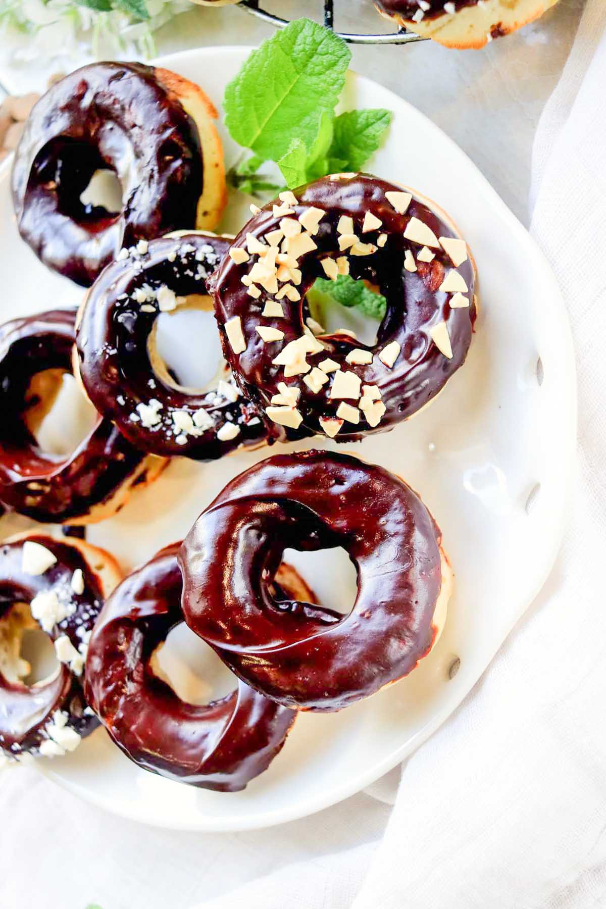 Chocolate frosted donuts sprinkled with chopped nuts.