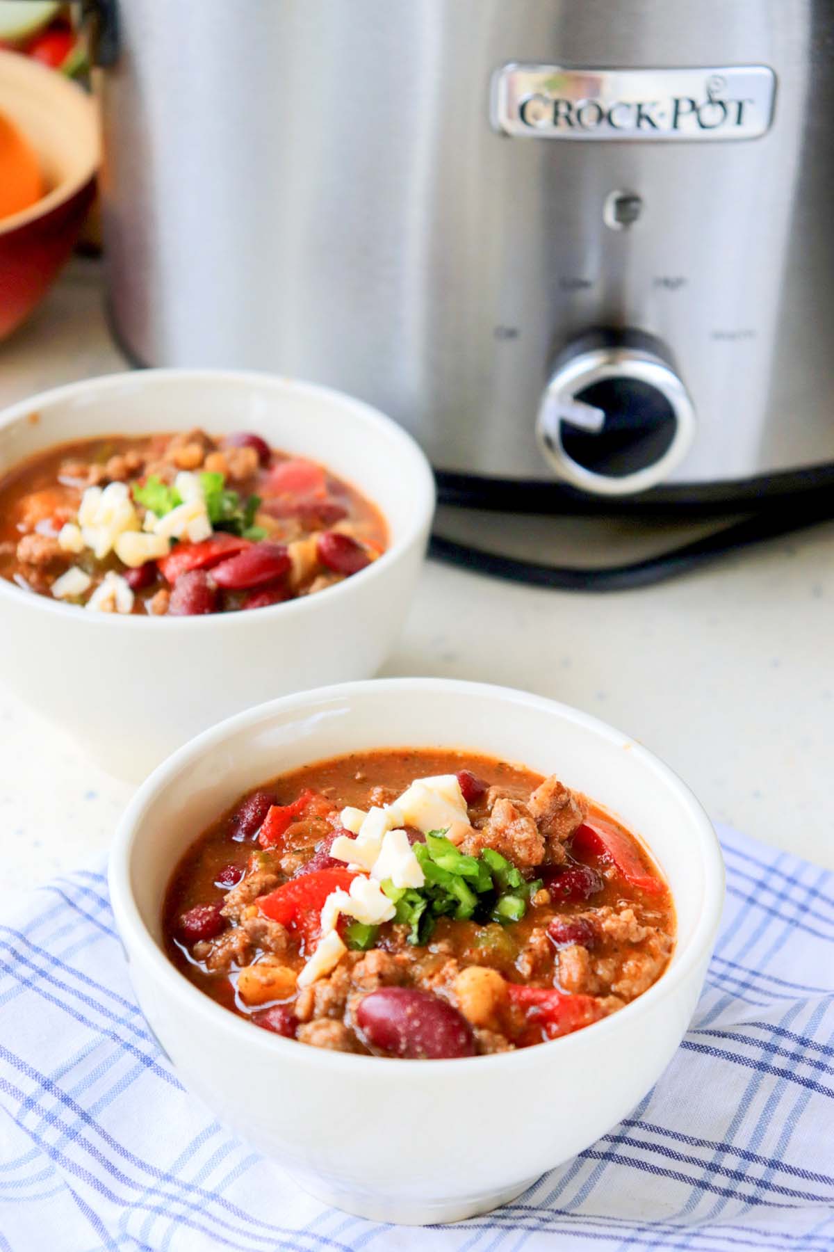 Two bowls of chili in front of the slow cooker.