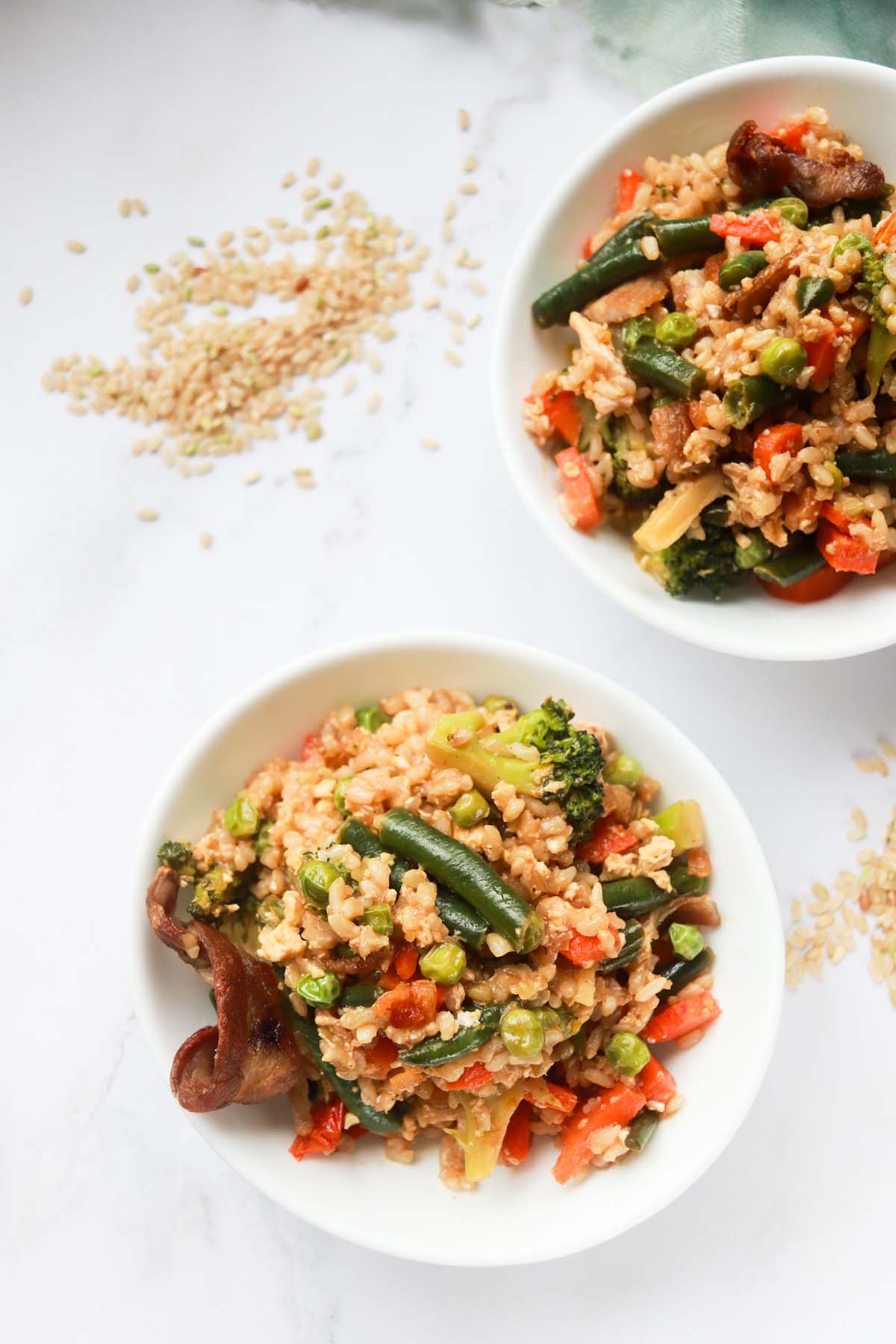 Two bowls of fried rice on a white table.