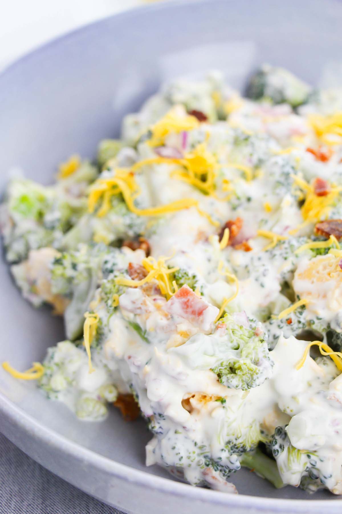 Broccoli salad topped with shredded cheese.