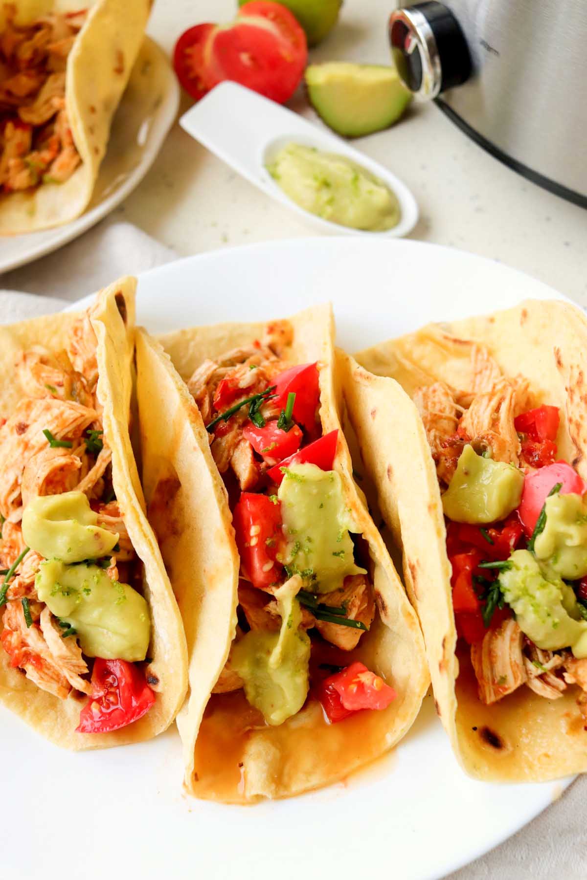 chicken tacos topped with avocado sauce.