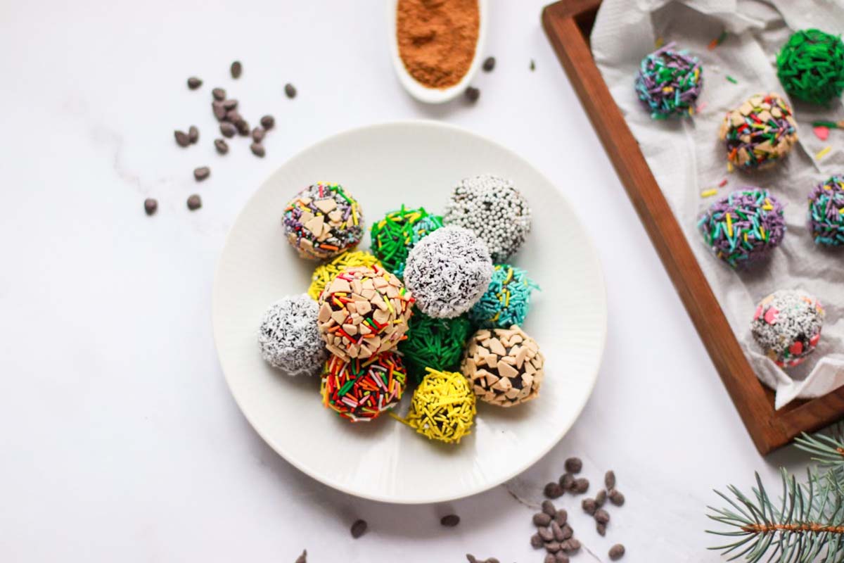 Truffles rolled in toppings on a white plate.