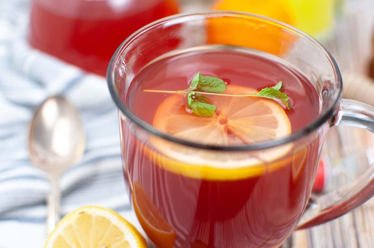 Tea in a glass with a lemon slice and a sprig of mint.