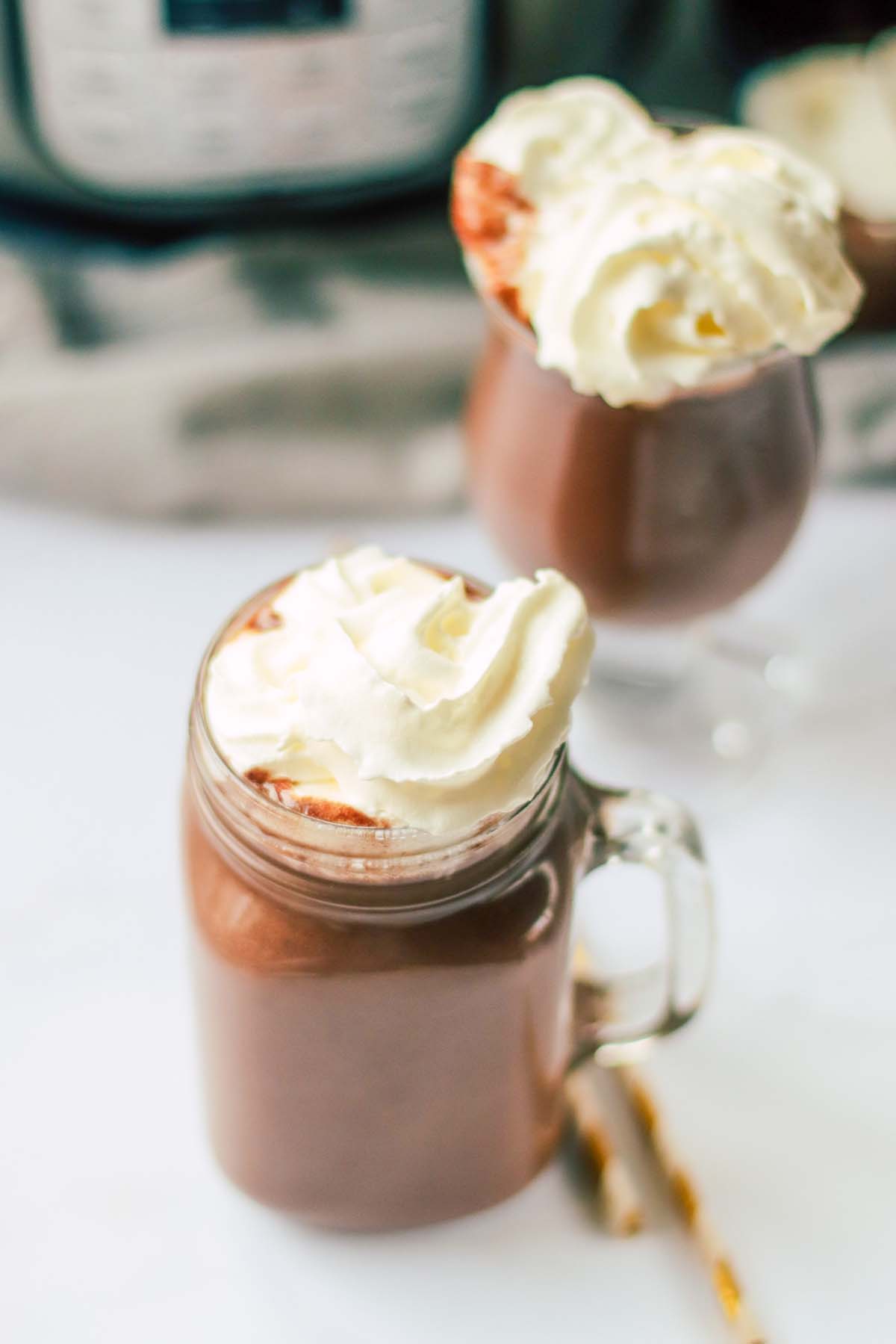Two glasses of hot chocolate topped with whipped cream.