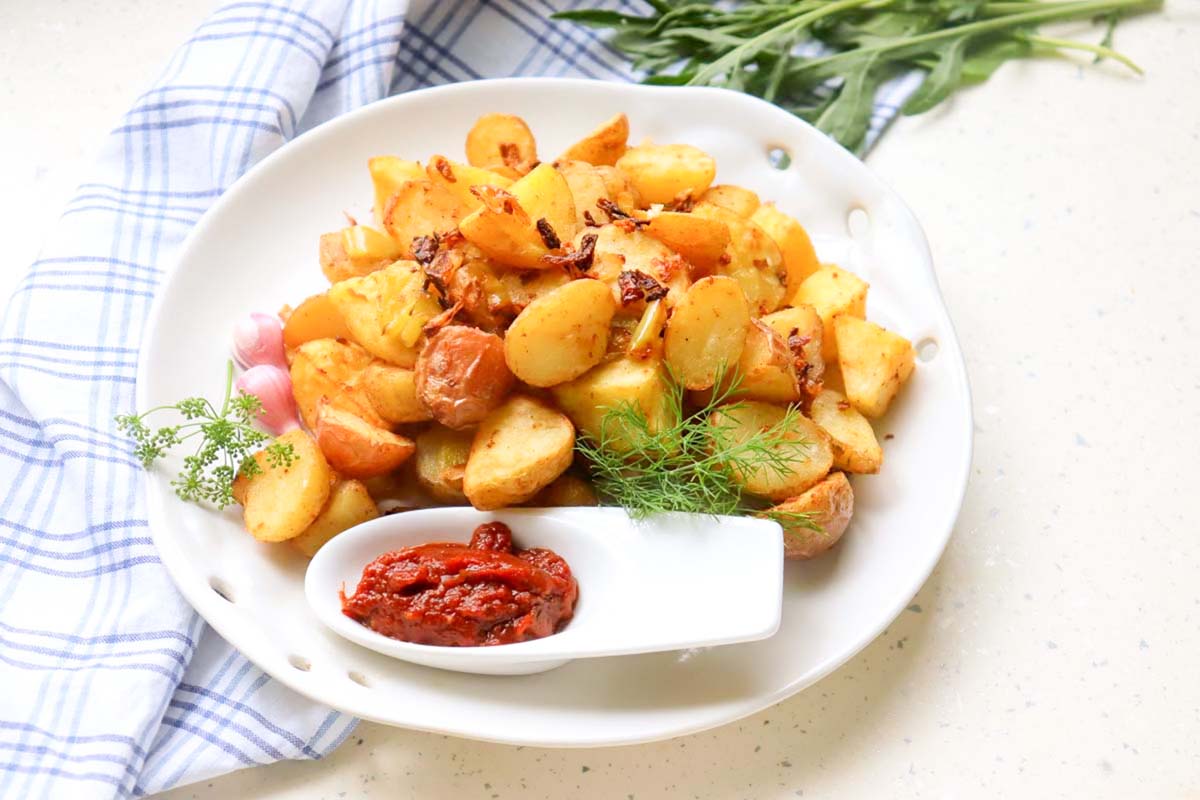 Potatoes on a plate with ketchup.
