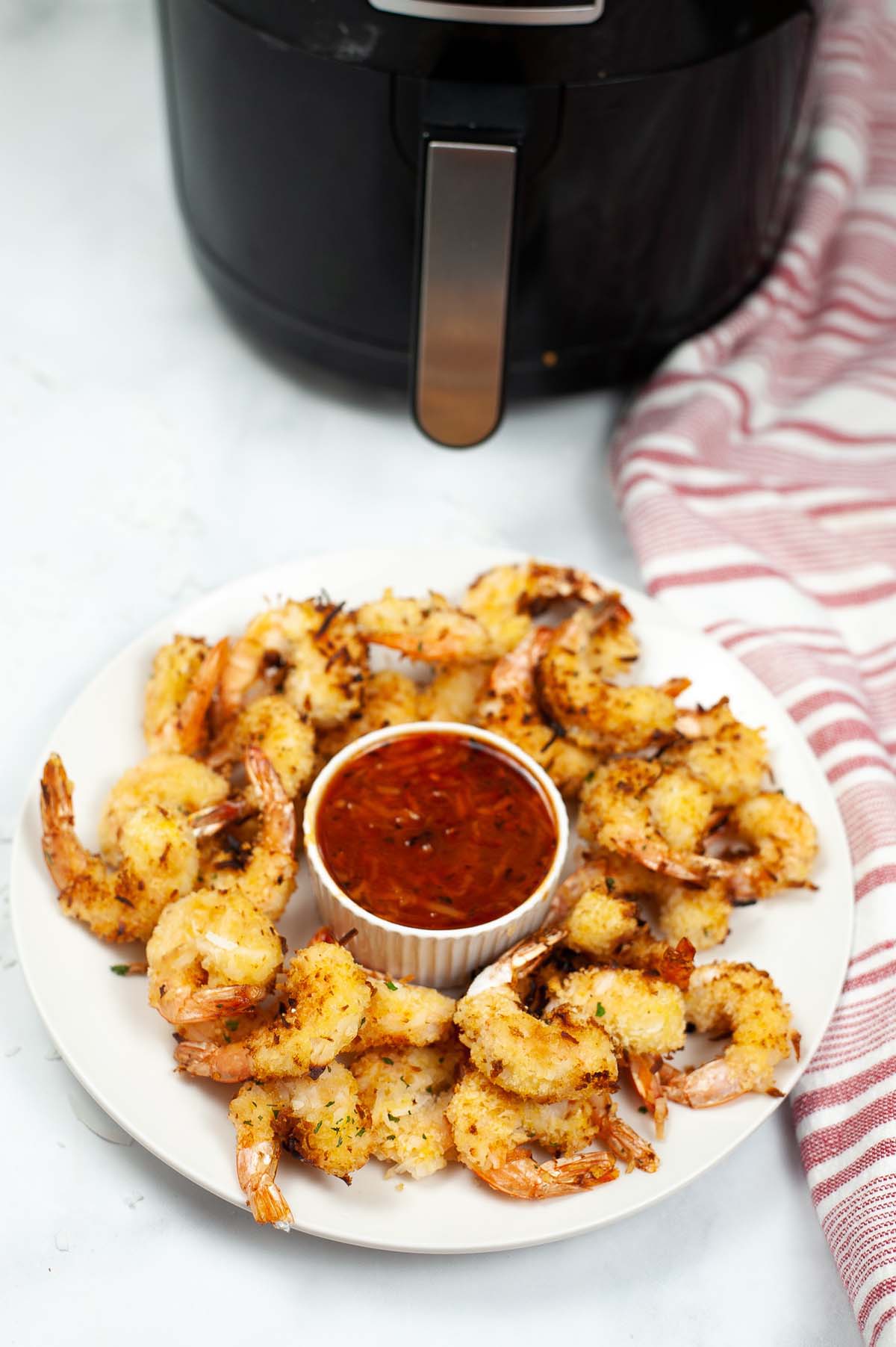 plate of coconut shrimp in front of air fryer.