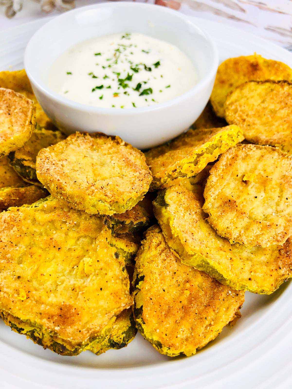 Fried pickles next to a bowl of ranch dip.