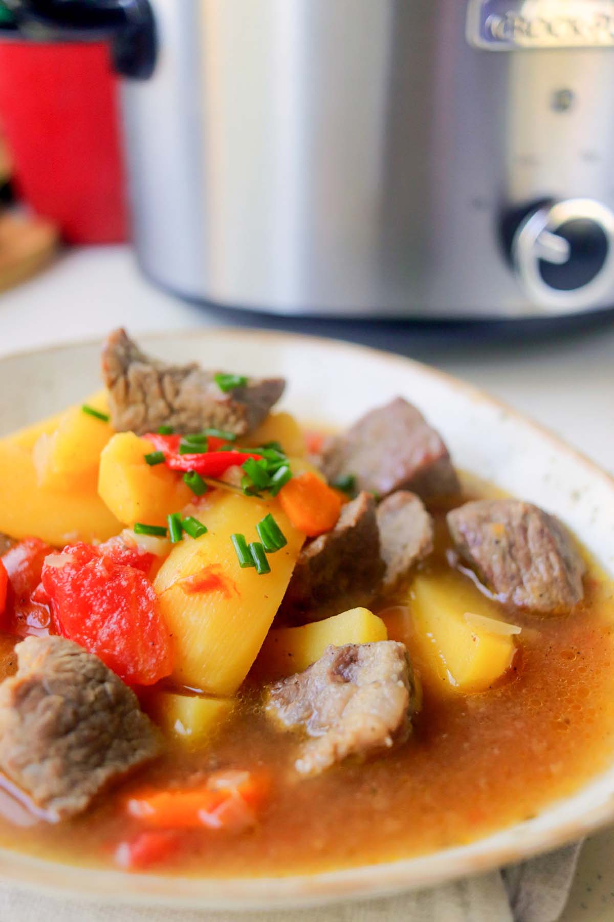 Beef stew in a bowl set on a white table.