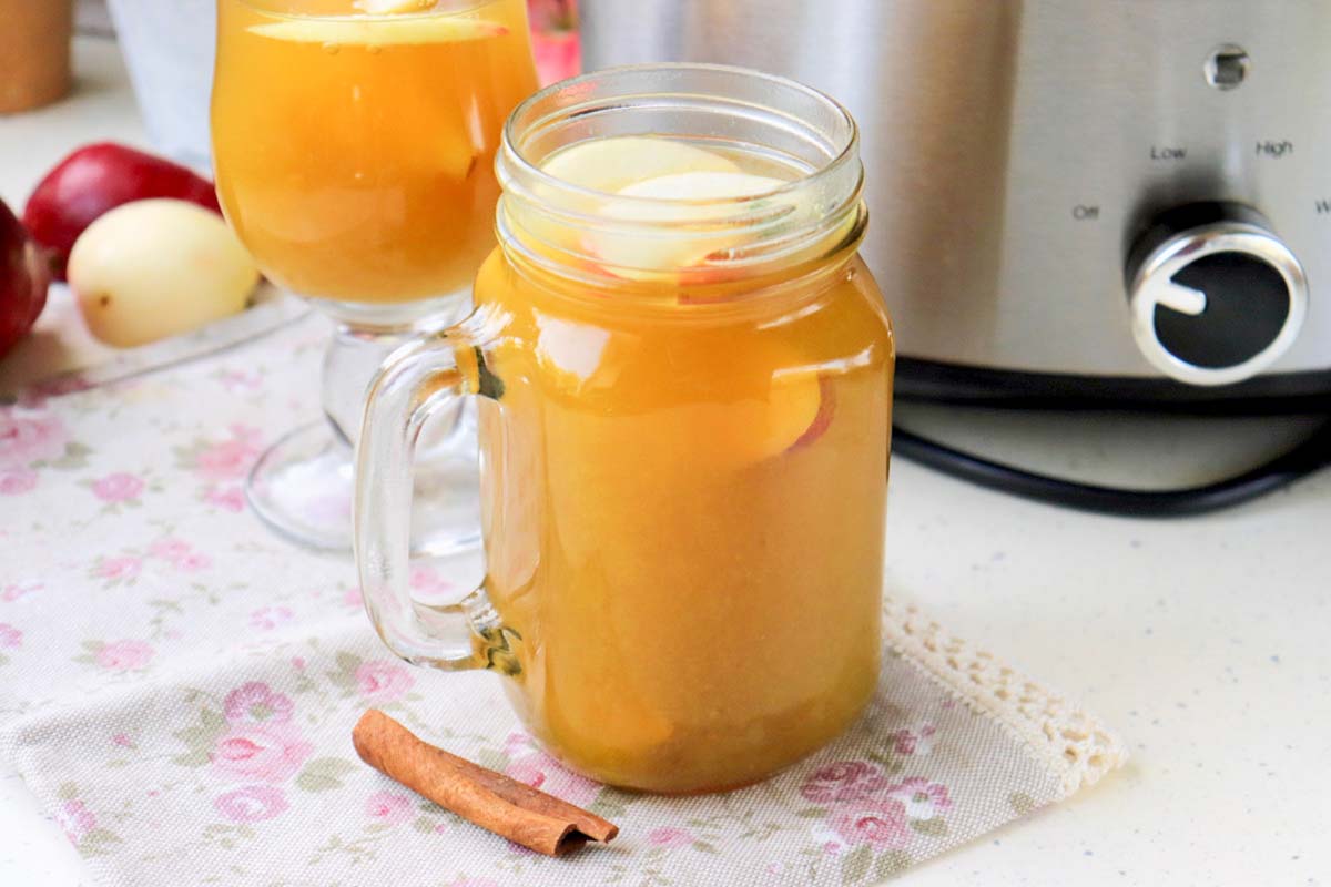 Cider in a glass in front of the Crock Pot.